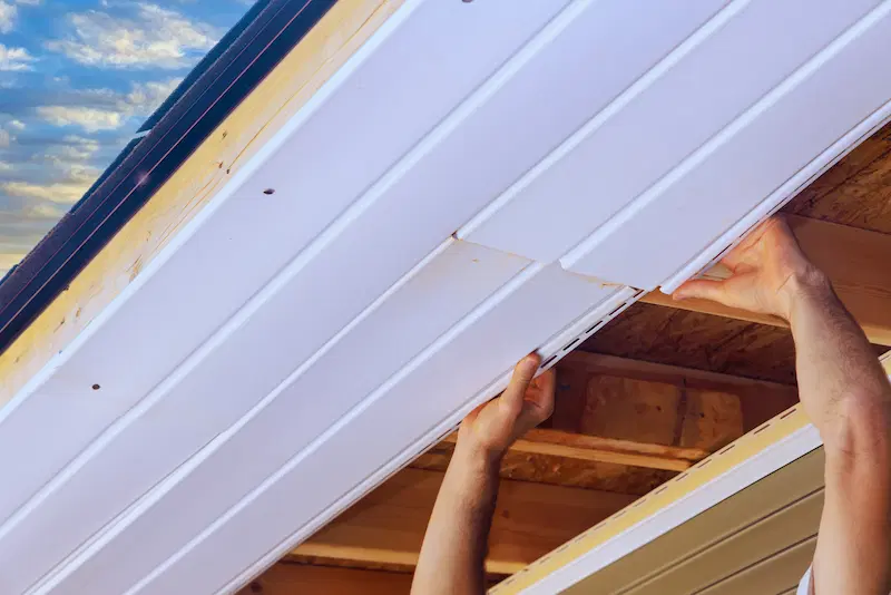 A roofer installing vinyl soffits in a home